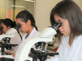 Personas viendo el microscopio en un laboratorio de la Universidad de Caldas
